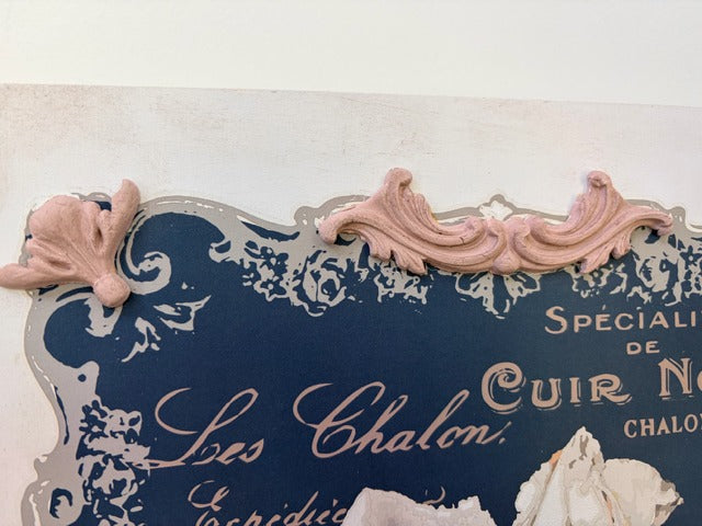 Decorative sign with ornate design and text on a white background