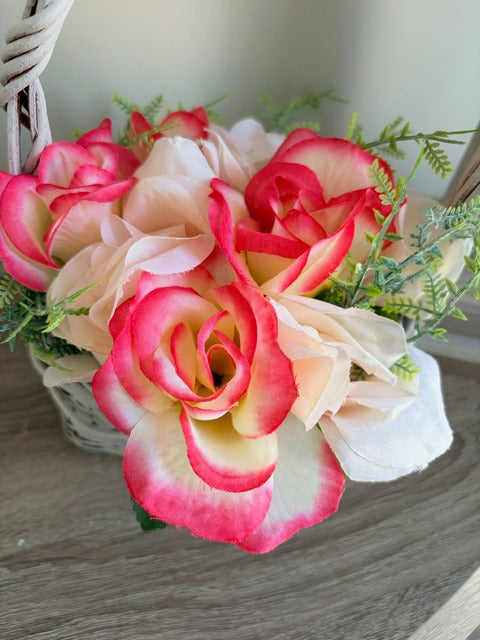 Bouquet of pink and white roses with greenery on a wooden surface