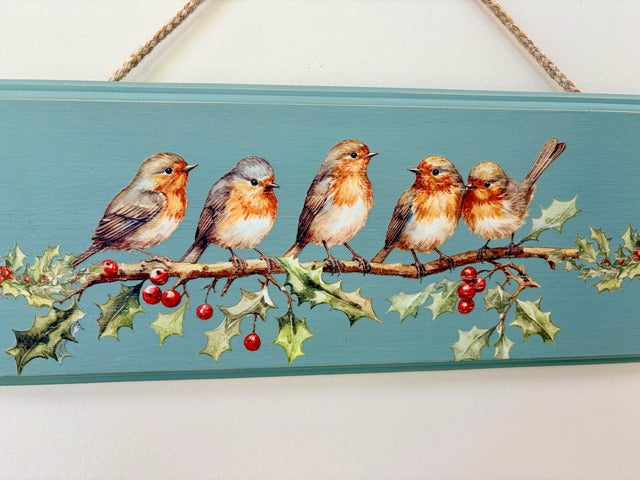 Decorative sign with painted birds and holly on a blue background