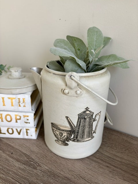 Metal teapot with plant on a wooden surface
