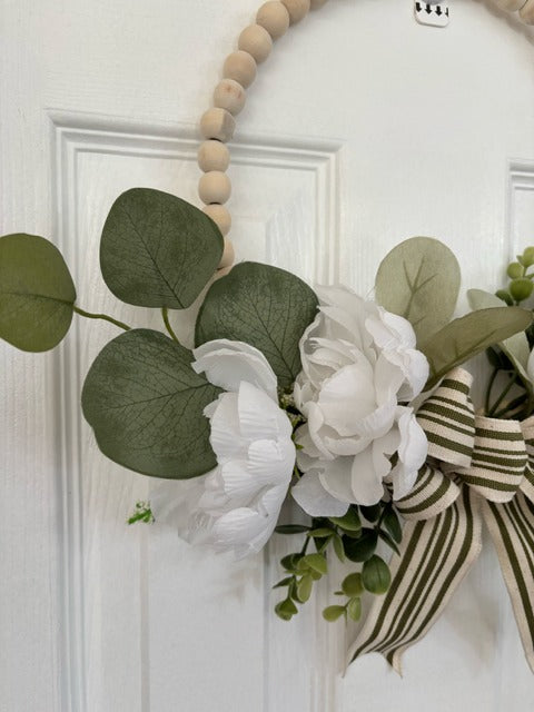 Decorative wreath with flowers and a bow on a white door
