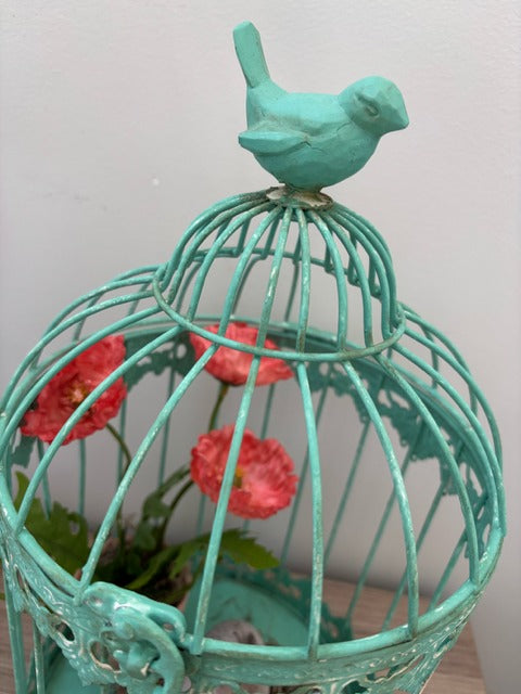 Decorative teal birdcage with plants and eggs
