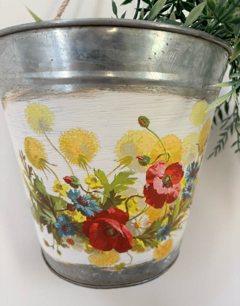 Metal bucket with floral decal on a white surface