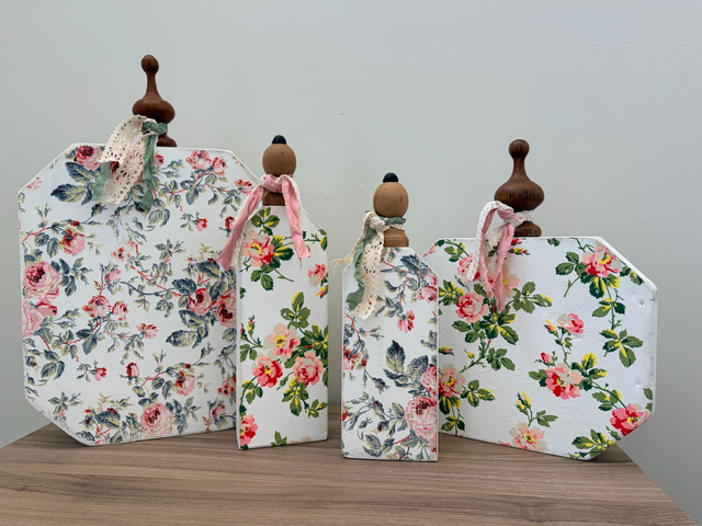 Wood pumpkins with floral designs and ribbons around stems.