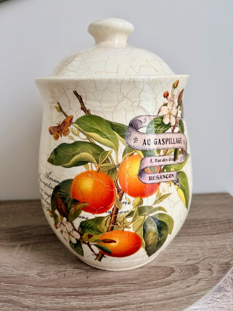 Decorative ceramic jar with fruit design on a wooden surface