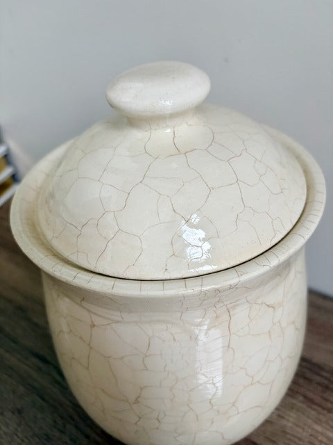 white ceramic canister with a cracked glaze pattern on a wooden surface.