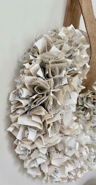 Wreath made of folded sheet music with a brown ribbon on a light background
