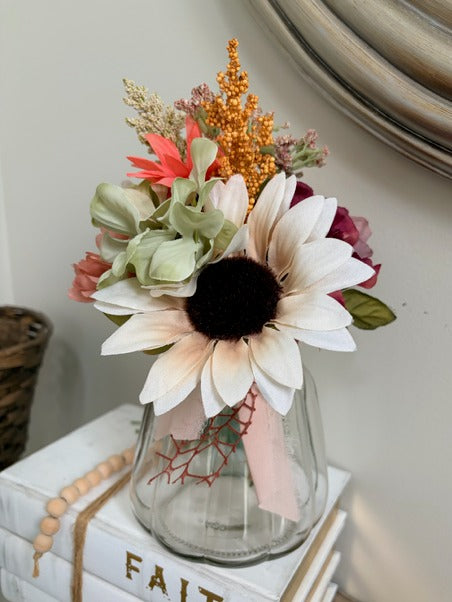 Bouquet of flowers in a glass vase on a white surface with a blurred background