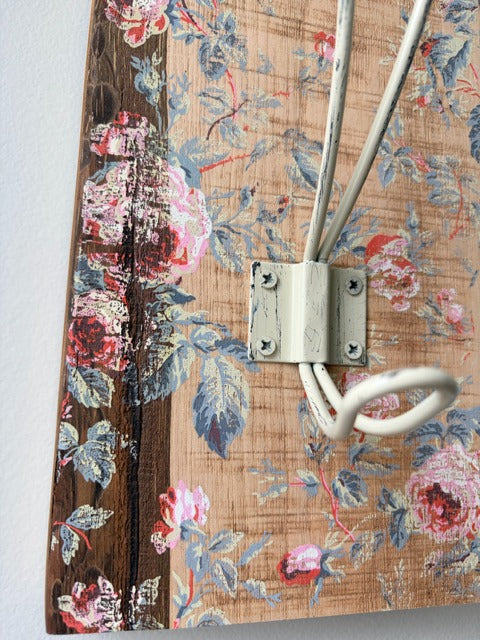 Floral-patterned board with metal hooks on a plain background