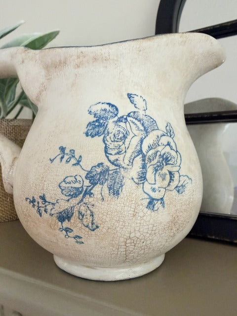 White ceramic pitcher with blue floral design on a surface