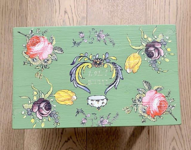 Decorative stool with floral and paisley designs on a wooden surface