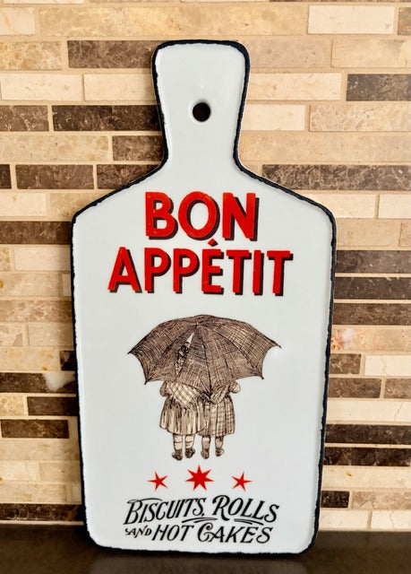 Decorative cutting board with 'Bon Appetit' text and illustration on a wooden background