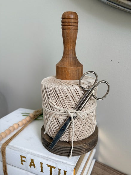 Wooden spool of twine with scissors on a white surface