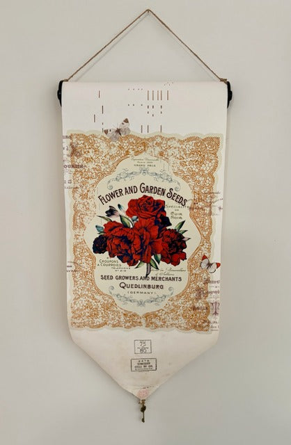 Decorative piano roll banner with floral design and text on a plain wall