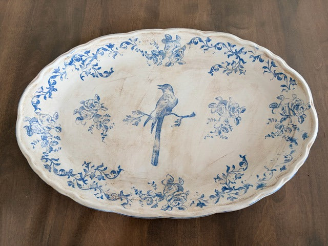 Decorative plate with blue floral and bird pattern on a wooden surface