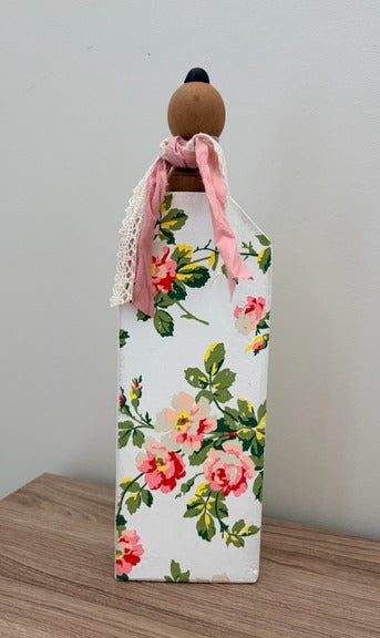 Decorative pumpkin with floral design and pink ribbon on a wooden surface