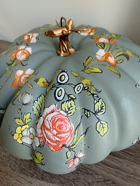Decorative pumpkin with floral designs on a wooden surface