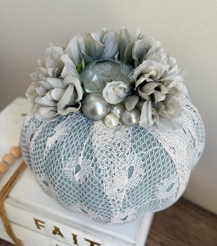 Decorative pumpkin with lace and flowers on a white surface