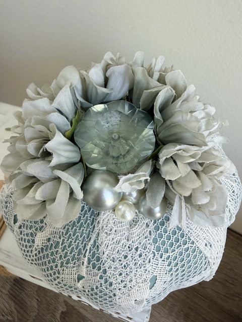 Decorative pumpkin with flowers and pearls on a white lace background