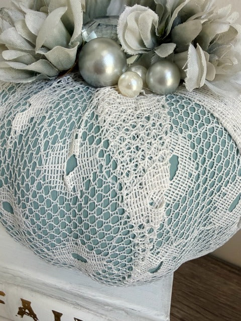 Decorative pumpkin with lace and ornaments on a white surface