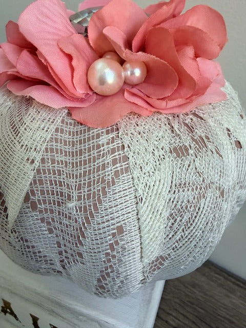 Decorative pumpkin with pink flowers and pearls on a textured surface