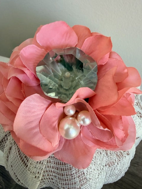 Pink flower with a crystal knob 
and pearls on a textured surface