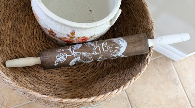 Wooden rolling pin with floral design on a woven mat