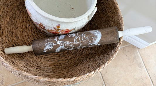 Wooden rolling pin with floral design on a woven mat