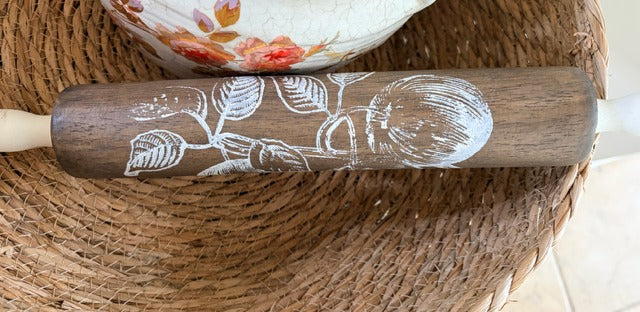 Wooden rolling pin with floral design on a textured surface