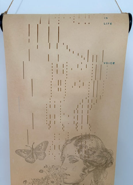 Decorative wall hanging with a woman's face, butterfly, and text on a beige background.