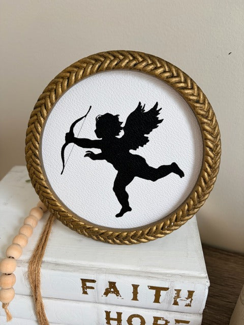Decorative item with a silhouette of a cherub in a gold frame