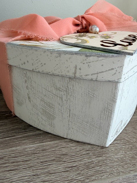 White textured box with a pink fabric and decorative item 