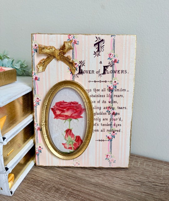 Decorative panel with a red rose design and text on a wooden surface.
