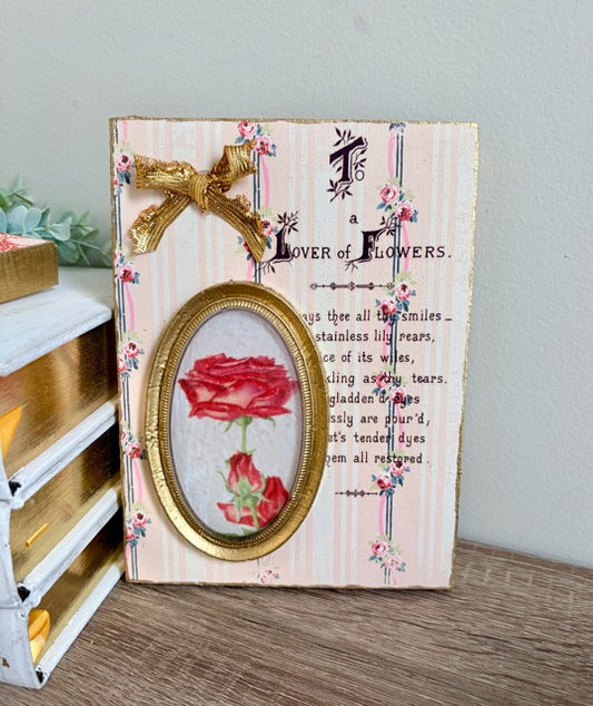 Decorative panel with a red rose design and text on a wooden surface.