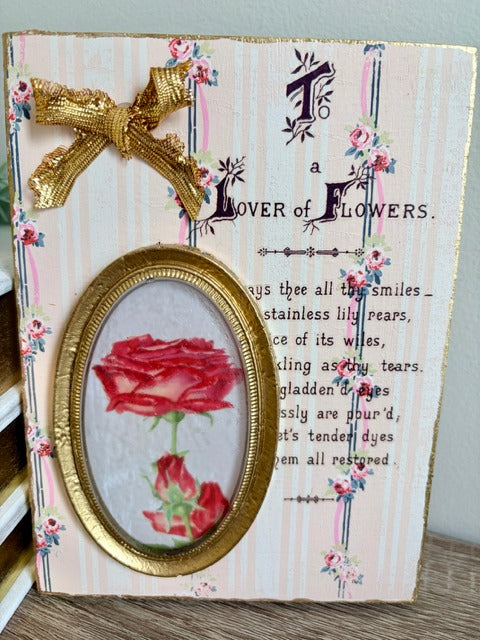 Decorative panel with a red rose in a gold frame, floral design, and text on a striped background.