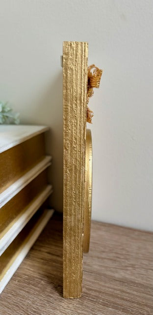 Gold decorative item on a shelf against a neutral wall