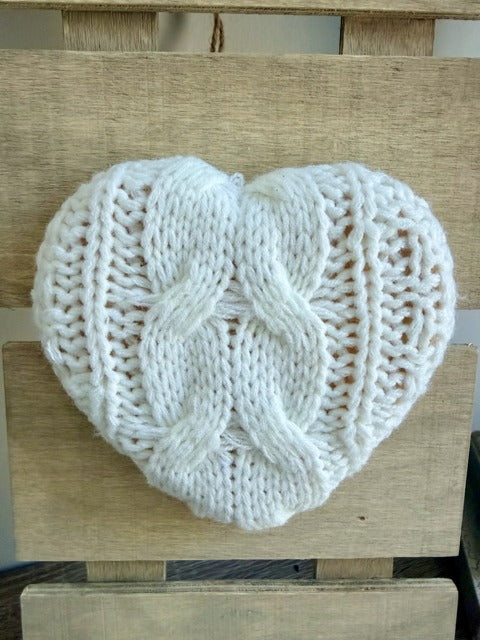 White knitted heart-shaped object on a wooden surface