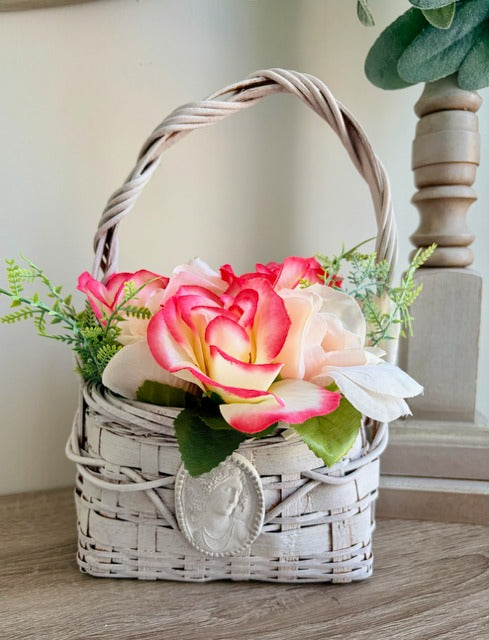Wicker basket with artificial flowers on a wooden surface