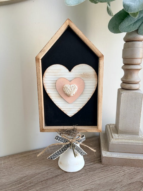 Decorative heart-shaped object in a wooden frame on a stand 