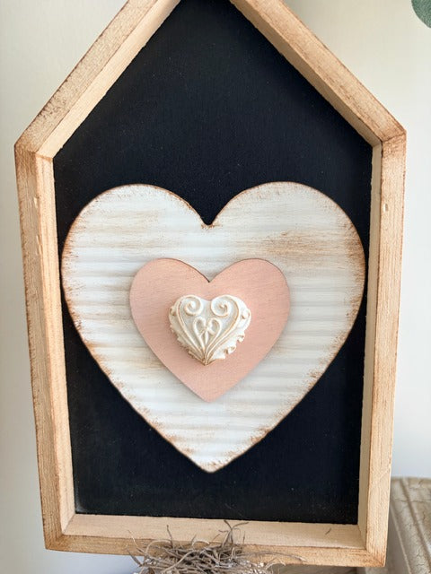 Heart-shaped decorative item in a wooden frame on a black background