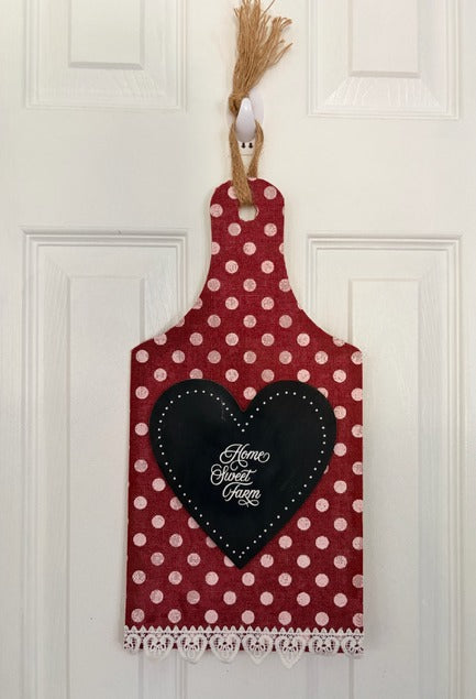 Decorative cutting board with red polka dot pattern and black heart-shaped sign on a white door.