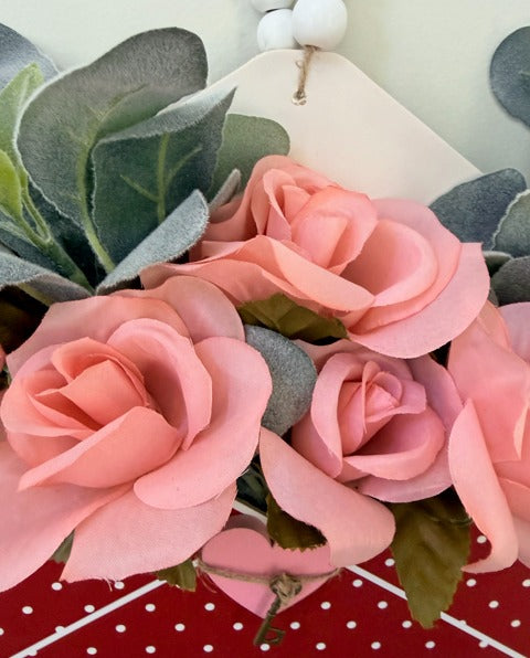 Pink flowers with green leaves on a red and white polka dot background
