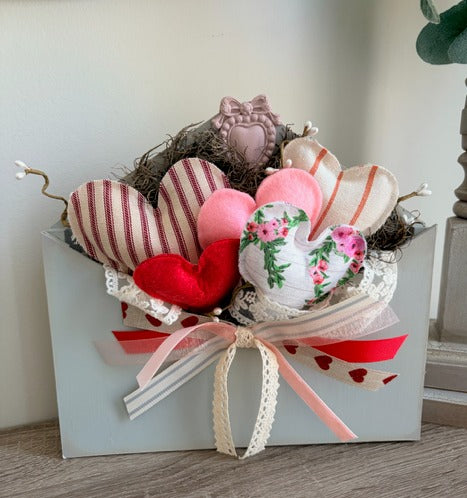 Heart-shaped decorative items in a box with a bow on a wooden surface.