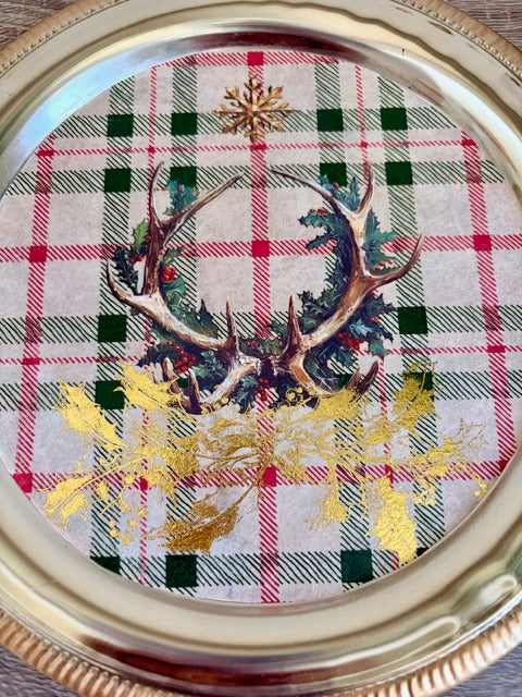 Decorative plate with plaid pattern, antlers, and gold leaves on a white background