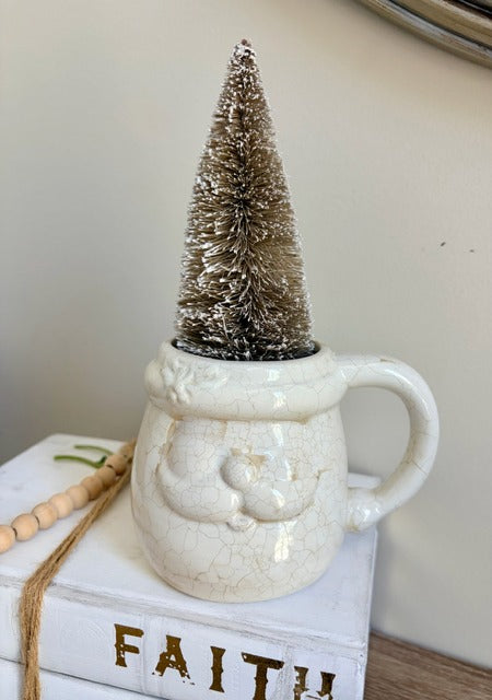 White ceramic mug with a textured surface, containing a small taupe Christmas tree