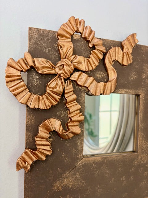 Decorative wall mirror with intricate gold bow