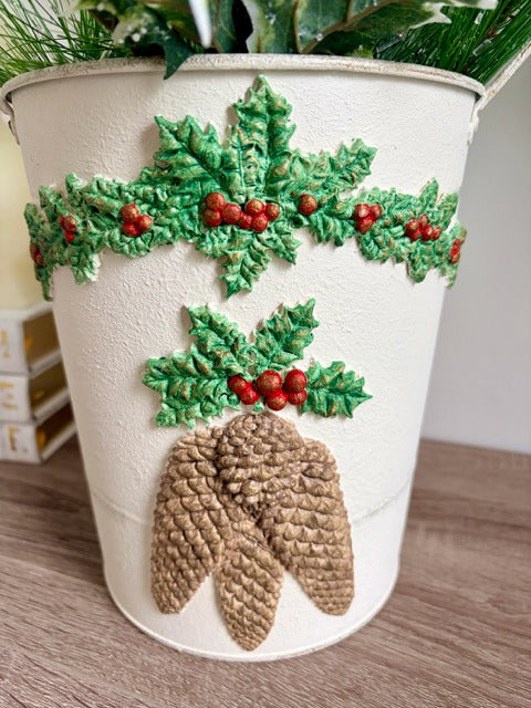 Decorative white bucket with holly leaves and pinecones 