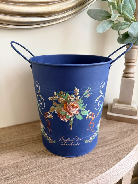 Blue metal bucket with floral design on a wooden surface
