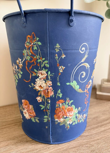 Blue bucket with floral pattern on a wooden surface