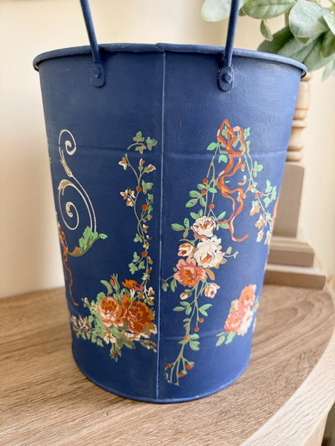 Blue floral-patterned bucket on a wooden surface